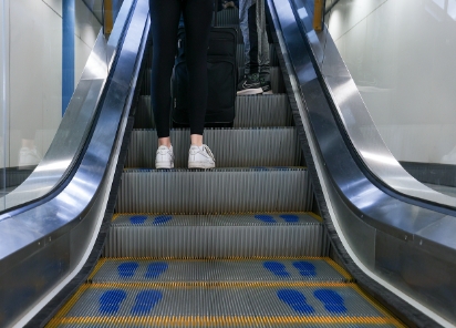 An individual on an escalator with blue footprints, going upwards