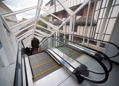 Escalator in a glass building with a man going down