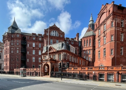 An impressive historic listed building, featuring a large red brick facade and an abundance of windows