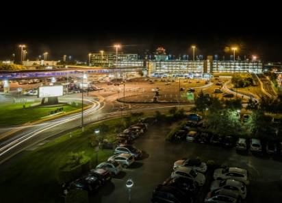 A nighttime view of an airport parking lot filled with parked cars