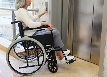 A woman sat in a wheelchair waiting in front of a disabled access lift