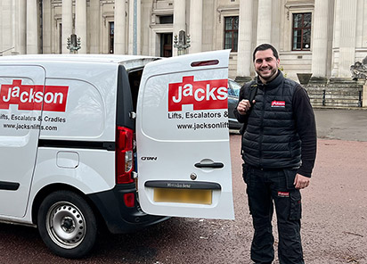 A lift engineer arriving on-site standing next to a white van with the Jackson Logo on it